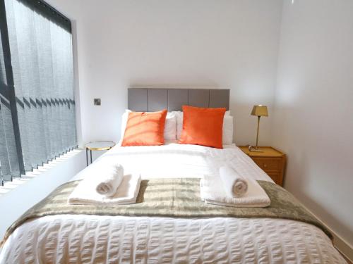 a bedroom with a large white bed with orange pillows at Pass the Keys Mill Conversion Flat Mins from City Bars Shops in Manchester