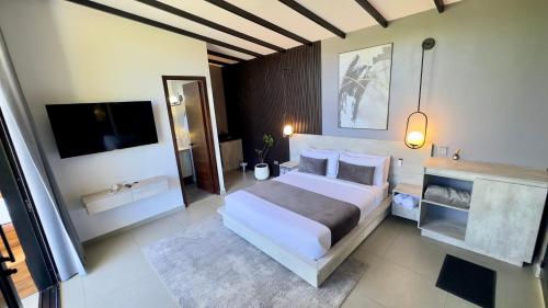 a bedroom with a large white bed and a flat screen tv at Rooca Habitat Guatape in Guatapé