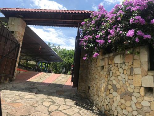 a stone wall with flowers on top of it at Casa Campestre Villateresita in Anapoima