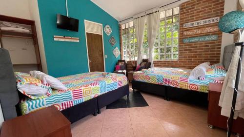 two beds in a room with blue walls at Casa Campestre Villateresita in Anapoima
