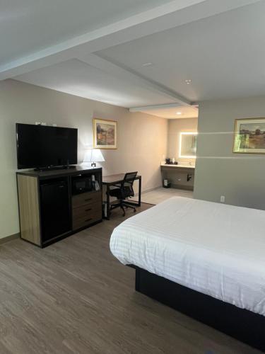 a hotel room with a bed and a flat screen tv at Northern Queen Inn in Nevada City
