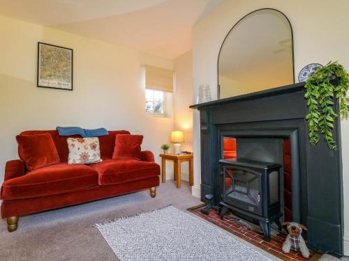 a living room with a red couch and a fireplace at Holmhurst in Southwell