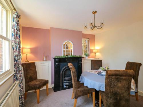a dining room with a table and a fireplace at Holmhurst in Southwell
