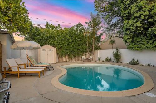 a swimming pool with chairs and an umbrella at Lake Balboa Hideaway in Los Angeles