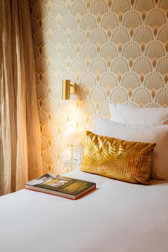a book on top of a bed with a pillow at Hôtel Artemisia Montmartre in Paris