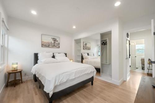 a white bedroom with a large bed and a mirror at Lake Balboa Hideaway in Los Angeles