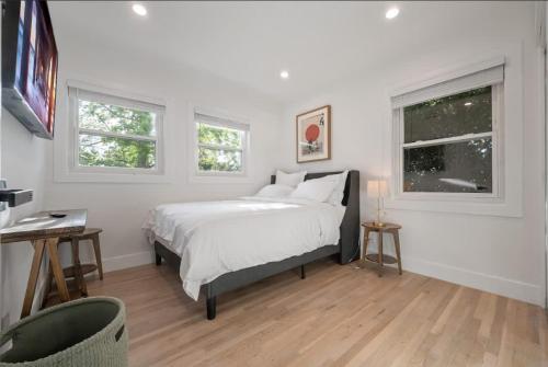 a white bedroom with a bed and two windows at Lake Balboa Hideaway in Los Angeles