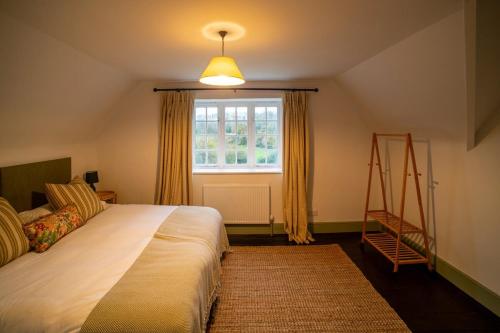 a bedroom with a bed and a window and a ladder at Luxury 2 Bed Woodland Cottage on Rewilding Estate in Beaminster