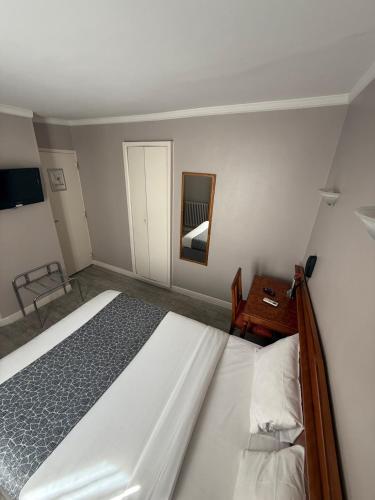 une chambre avec un lit, une table et un miroir dans l'établissement New Hôtel Gare Du Nord, à Paris