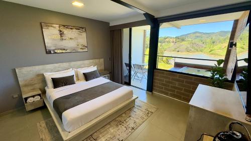 a bedroom with a large bed and a large window at Rooca Habitat Guatape in Guatapé