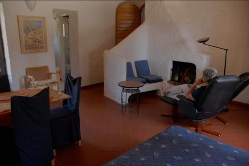 une femme assise sur une chaise dans un salon avec une cheminée dans l'établissement U Cipressu, à La Celle-sous-Gouzon