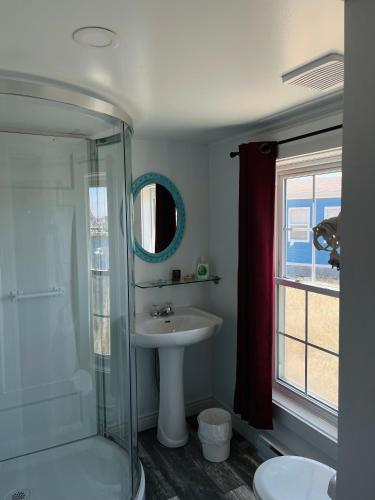 a bathroom with a sink and a glass shower at Toulinguet Inn - Suites in Twillingate