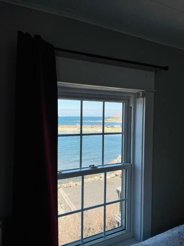a window in a room with a view of the ocean at Toulinguet Inn - Suites in Twillingate