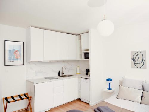 - une cuisine blanche avec des placards blancs et un canapé dans l'établissement Le signature - Magnifique Studio tout confort au coeur de Strasbourg, à Strasbourg