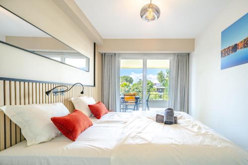 une chambre avec un grand lit blanc avec des oreillers rouges dans l'établissement Rooftop 3 pièces avec Piscine face mer, à Villeneuve-Loubet
