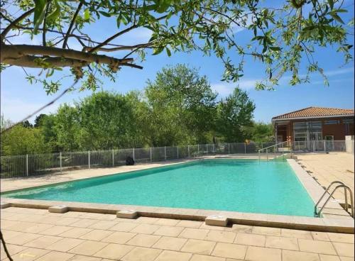 une grande piscine avec une clôture et un bâtiment dans l'établissement Chez francoise, à Saint-Saturnin-lès-Avignon