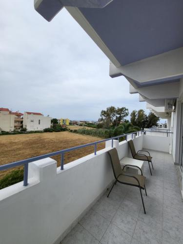 a balcony with two chairs and a view of a field at Pyrgos Hotel Apartments in Kremasti