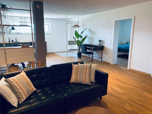 a living room with a black couch and a piano at Tolle Wohnung mit Seeblick in Zell am Moos