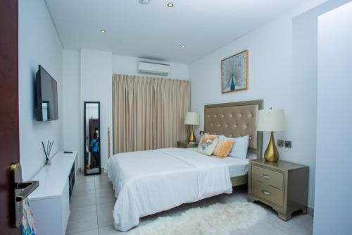 a bedroom with a white bed and a television at The Steward Dwellings@Signature in Accra