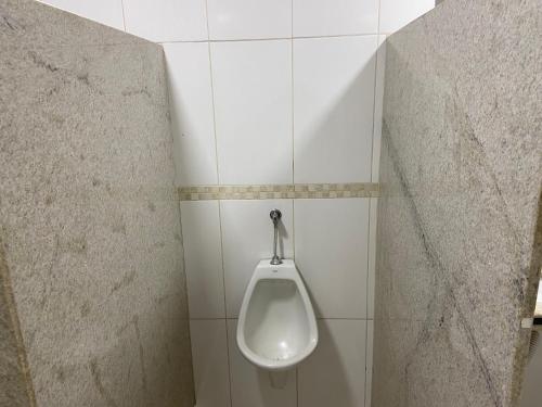 a bathroom with a urinal on a tiled wall at Vila Suítes Coliving in Vila Velha