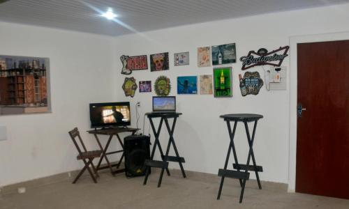 a room with two tables and a tv on a wall at Vila Suítes Coliving in Vila Velha