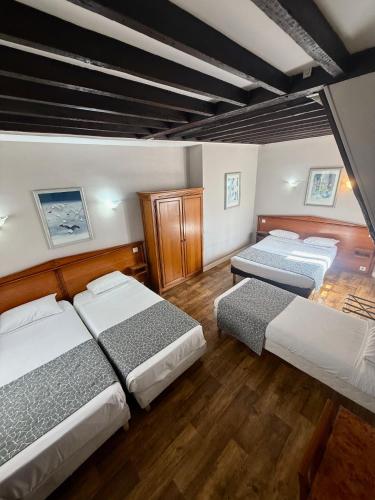 une chambre avec trois lits et du parquet dans l'établissement Hotel Richmond Gare du Nord, à Paris