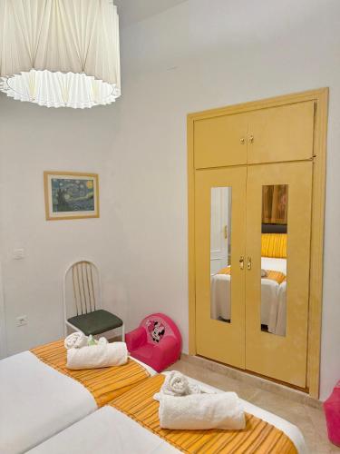 a bedroom with two beds and a chair with towels at Esencia Andalucia in Rociana