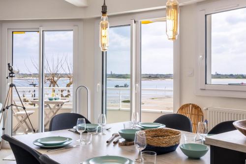 une salle à manger avec une table, des chaises et des fenêtres dans l'établissement Appartement vue mer, Arcachon 3 étoiles, à Arcachon