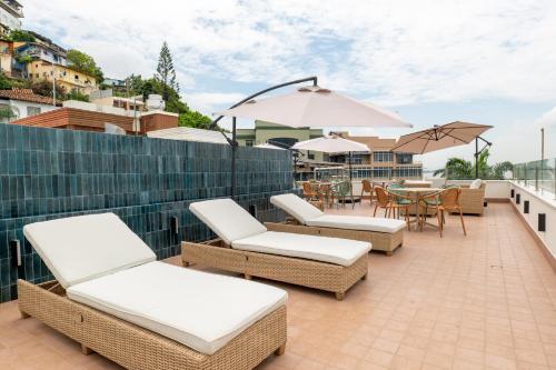 a patio with chairs and tables and umbrellas on a roof at Hotel Rio Guayas by Art Hotels in Guayaquil