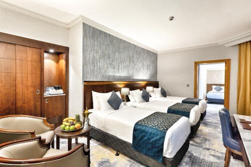 a hotel room with two beds and a table and chairs at Nozol Royal Inn Hotel in Al Madinah