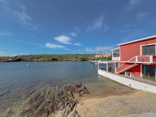 a red building sitting on the water next to at 49 Sea Rooms - Guesthouse by Host Hero in Stintino