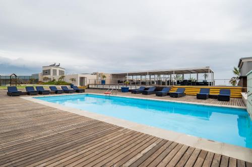 a swimming pool with lounge chairs on a deck at Lagoon Shoreline 2 Bedroom Apartment in Cape Town