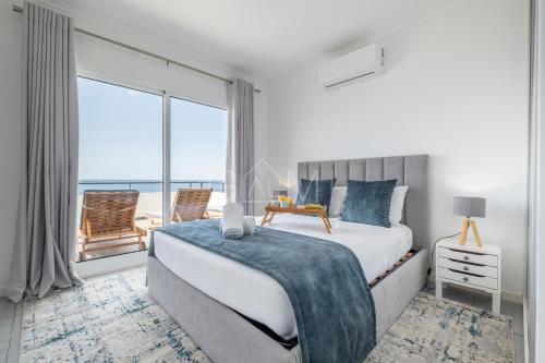 Un dormitorio con una cama y una ventana grande. en Esterinha's Ocean Apartment by GALMI, en Jardim do Mar