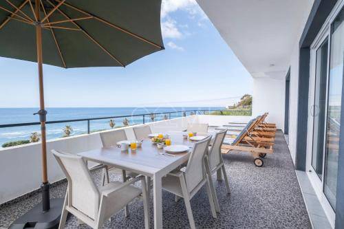 Una mesa blanca y sillas en un balcón con vista al mar. en Esterinha's Ocean Apartment by GALMI, en Jardim do Mar