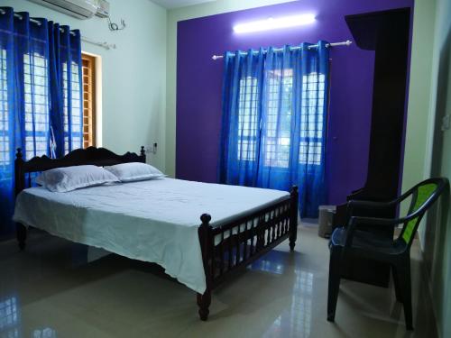 a bedroom with a bed with purple walls and a chair at Dream World Home in Kollam