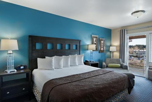 a bedroom with a large bed with a blue wall at Oxford Suites Silverdale in Silverdale
