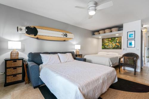 a bedroom with two beds and a surfboard on the wall at Big Island Kona Islander #341 by Coldwell Banker Island Vacations in Kailua-Kona