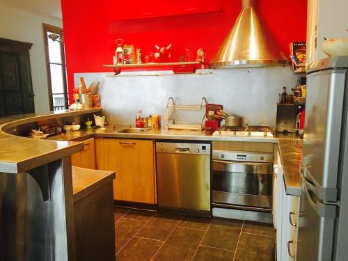une cuisine avec des murs rouges et des appareils en acier inoxydable dans l'établissement superbe 2 pièces au centre de paris, à Paris