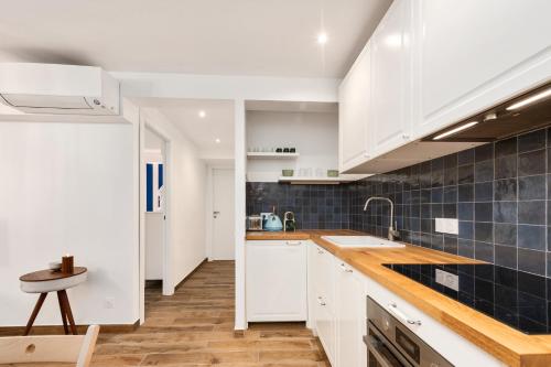 a kitchen with white cabinets and blue tiles on the wall at 2mn Monaco - Coquet appartement rénové - DM in Roquebrune-Cap-Martin