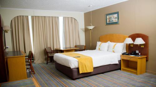a hotel room with a large bed and a desk at Holiday Inn - Bulawayo by IHG in Bulawayo