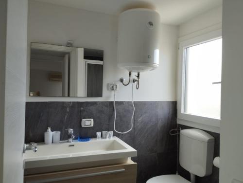 a bathroom with a sink and a toilet and a mirror at Fiore di Loto Rooms in Carini
