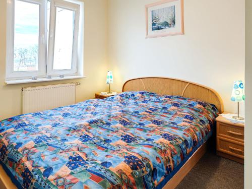 コウォブジェクにあるApartamenty Alessia Kołobrzegのベッドルーム1室(カラフルなキルトのベッド1台付)