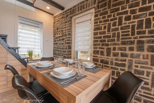 a dining room with a wooden table and a brick wall at Altitude Matra in Mátraszentimre