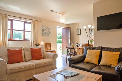 a living room with two couches and a table at Alpaca Cottage 7mins to Alton Towers in Denstone