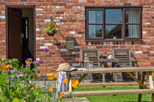 a table and chairs in front of a brick building at Alpaca Cottage 7mins to Alton Towers in Denstone