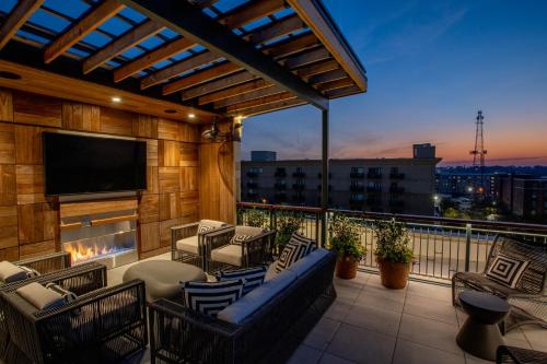 a balcony with a tv and a couch and chairs at The Bell Athens by Kasa in Athens