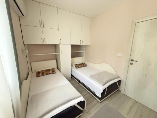 two beds in a small room with white cabinets at Apartmani Avanti Becici in Becici