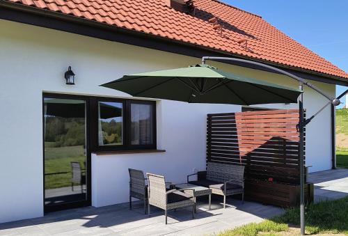 a table and chairs under an umbrella on a patio at Ptasi Zakątek in Tomaryny