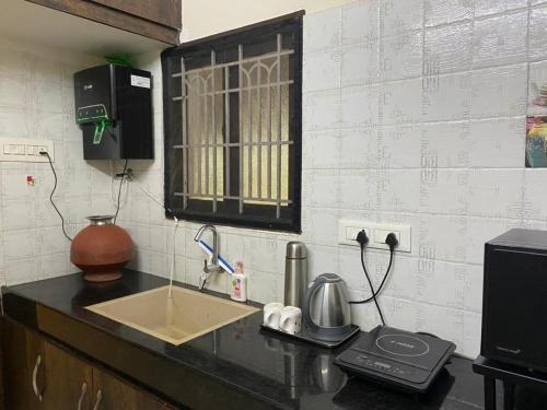 un comptoir de cuisine avec un évier et un micro-ondes dans l'établissement LBS Farmstay, à Alāndurai