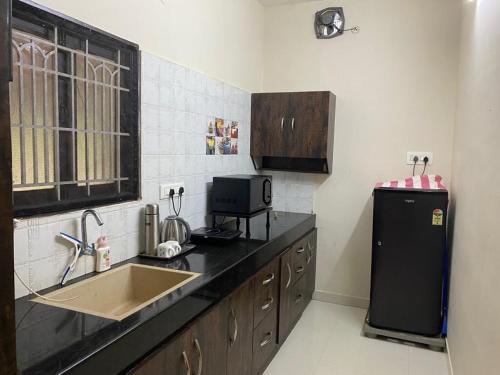 une cuisine avec un évier et un réfrigérateur dans l'établissement LBS Farmstay, à Alāndurai